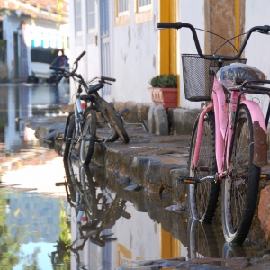 Bicycles parked by the kerb in Paraty, Brazil. The streets are flooding due to a very high tide coming in.